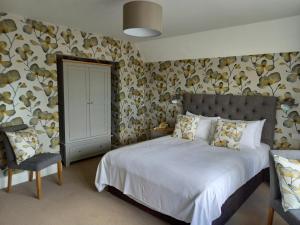 um quarto com uma cama grande e uma cadeira em Trelawne Hotel em Falmouth