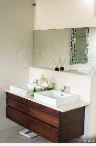 a bathroom with a white sink and a mirror at Precious Paradise Villa in Amanzimtoti