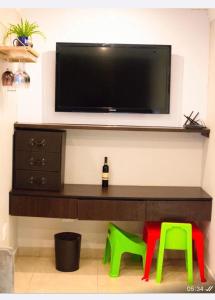 a living room with a tv and two green stools at Precious Paradise Villa in Amanzimtoti