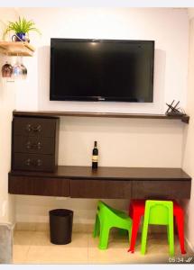 un soggiorno con TV e 2 sgabelli verdi di Precious Paradise Villa ad Amanzimtoti
