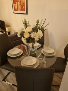 a dining room table with plates and flowers on it at The Symphony Apartment in Liverpool