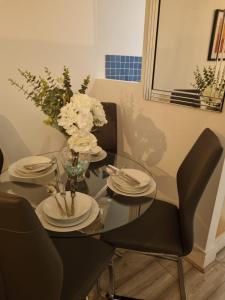 a dining room table with plates and flowers on it at The Symphony Apartment in Liverpool