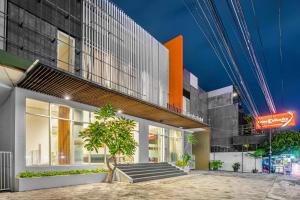 un edificio con un árbol delante de él en Sans Hotel Prime Cailendra Yogyakarta by RedDoorz, en Yogyakarta