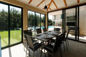 a dining room with a table and chairs and windows at Villa Marta Luxury House with Heated Pool in Plano