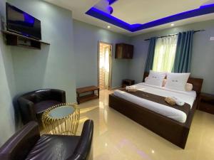 a bedroom with a bed and a tv and a chair at Human hotel Ivato in Antananarivo