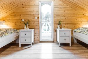 two beds in a room with wooden walls at Słoneczny Zagajnik-domek na skraju lasu, Roztocze, Zwierzyniec in Lipowiec