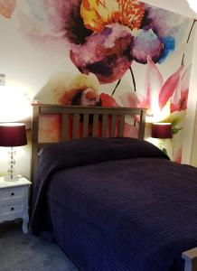 a bedroom with a bed with a flower mural on the wall at The Snug at Plover Cottage Lindley in Huddersfield