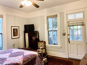 a bedroom with a bed and windows and a ceiling fan at Brackenridge House Bed and Breakfast in San Antonio
