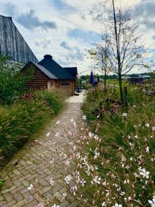 a brick path next to a house and flowers at Luxe Finse Kota van de Zandhoef in Eersel