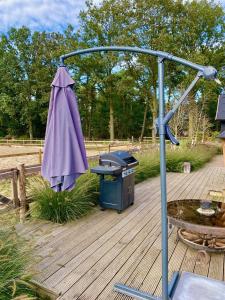 a grill and an umbrella on a wooden deck at Luxe Finse Kota van de Zandhoef in Eersel