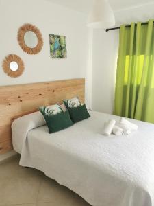 1 dormitorio con 1 cama con almohadas verdes y blancas en Centro de Corralejo con vistas a Isla de Lobos, en Corralejo