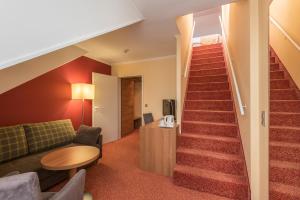 a living room with a staircase with a couch and a table at Holiday Inn Munich Unterhaching, an IHG Hotel in Unterhaching