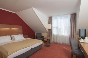 ein Hotelzimmer mit einem Bett und einem TV in der Unterkunft Holiday Inn Munich Unterhaching, an IHG Hotel in Unterhaching