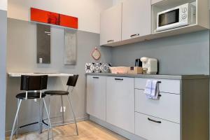una cucina con armadi bianchi, forno a microonde e sgabello di Sébastien's studio Calm Fully equipped #A2 a Grenoble