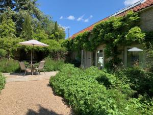 a patio with an umbrella and a table and chairs at Noelle’s Cottages, The Barn in Pickering