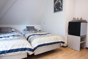 a bedroom with two beds and a flat screen tv at Logies De Witte Hoeve in Oudenaarde