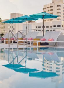 basen ze stołami i parasolami w budynku w obiekcie Hotel Greystone - Adults Only w Miami Beach