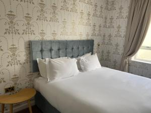 a bed with white pillows in a bedroom with wallpaper at RainHill Hall Hotel in Rainhull