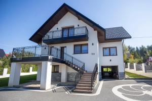 a white house with stairs and a balcony at Willa pod Halą Krupową in Skawica