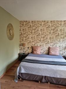 1 dormitorio con 1 cama con pared de piedra en Le Manoir De Morimont, en Céroux-Mousty