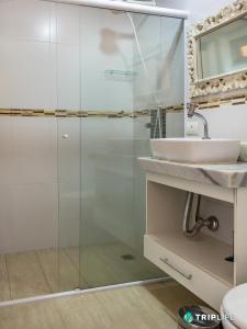 uma casa de banho com uma cabina de duche em vidro e um lavatório. em Casa Mandalê em Ilhabela