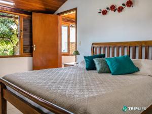 um quarto com uma cama grande e almofadas azuis em Casa Mandalê em Ilhabela