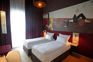 a hotel room with two beds and a painting on the wall at Grimm´s Berlin Potsdam in Teltow