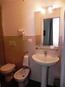 uma casa de banho com um lavatório, um WC e um espelho. em Palazzo Gropallo Rooms em Génova