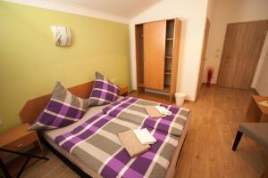 a bedroom with a bed with purple and gray sheets at Pension Diener in Naußlitz