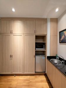 a kitchen with wooden cabinets and a sink and a microwave at Via Renata Prapanca in Jakarta