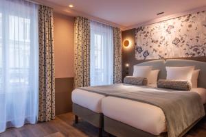 um quarto com uma grande cama branca e janelas em Maison Axel Opéra em Paris