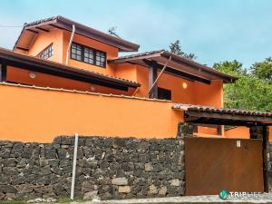 uma casa laranja com um muro de pedra e um portão em Morada dos Pássaros | Pertinho da Praia do Curral em Ilhabela