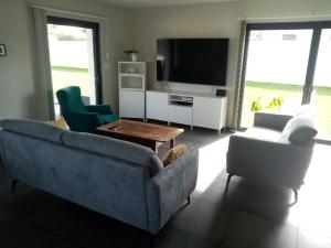 Un air de campagne في مونتوبان: غرفة معيشة مع أريكة وكراسي وتلفزيون