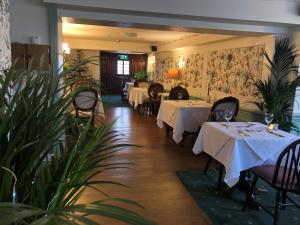a dining room with tables and chairs and plants at The Swan Inn in Sturminster Newton