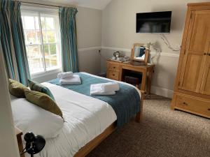 a bedroom with two beds and a tv and a window at The Swan Inn in Sturminster Newton