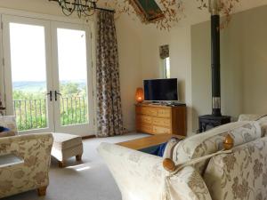 a living room with a couch and a tv and windows at Little Evanses in Axminster