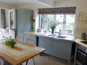 a kitchen with a sink and a table and a window at Little Evanses in Axminster
