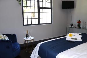 ein Schlafzimmer mit einem Bett, einem blauen Stuhl und einem Fenster in der Unterkunft Uzuri Lifestyle in Port St Johns