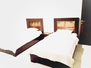 a bedroom with a white bed with a wooden headboard at Jade Dragon Hotel DHA Lahore in Lahore