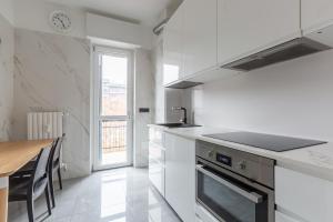 a white kitchen with a table and a counter top at BnButler - Largo Promessi Sposi - Moderno e Confortevole in Milan