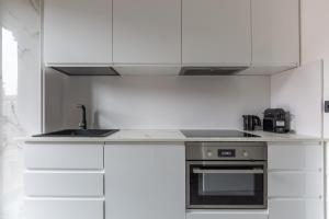 a kitchen with white cabinets and a stove top oven at BnButler - Largo Promessi Sposi - Moderno e Confortevole in Milan