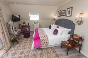 a bedroom with a bed and a table and a tv at Baruch Guest House in Stellenbosch