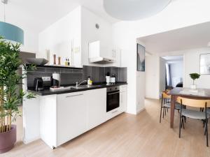 a kitchen with white cabinets and a dining table at limehome Berlin Neue Straße in Berlin