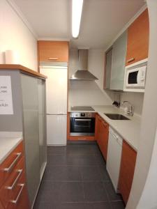 a small kitchen with white counters and wooden cabinets at Apartamento Ana Elgoibar con garaje in Elgóibar