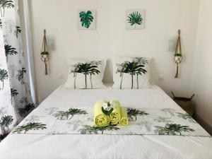 een slaapkamer met een wit bed met bloemen erop bij COEUR TIARE studio lounge piscine plage cocotiers in Saint-François