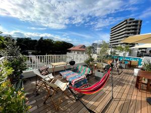 eine Terrasse mit Hängematte und Stühlen auf dem Balkon in der Unterkunft Hostel Have a Nice Day! ドミトリー 個室ルームあり#HVNI in Odawara