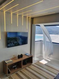 sala de estar con TV y ventana grande en Lindo apto tudo novinho, prédio frente mar, en Balneário Camboriú