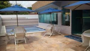 a patio with chairs and umbrellas on a house at Praia dos Carneiros Flat Hotel Apto Completo in Tamandaré