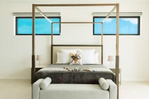 a bedroom with a large bed with two windows at Paradiso Del Mar, Turtle Tail, TCI in Turtle Cove