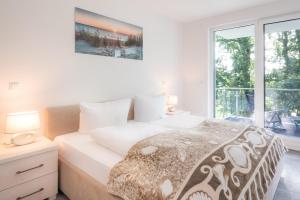 a white bedroom with a bed and a window at Apartment "Haffblick" - Haffresidenz in Garz